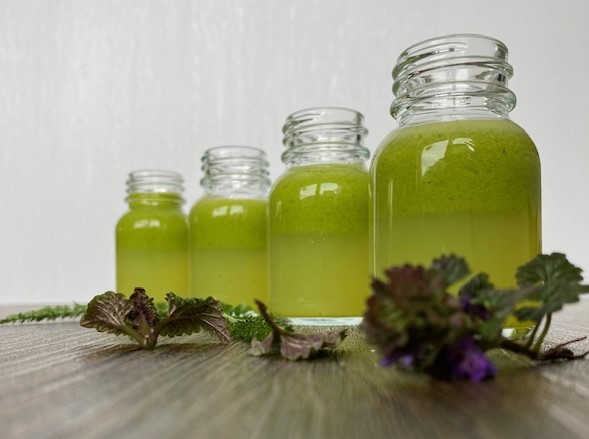Vier kleine Flaschen mit grünem Pflanzensaft
