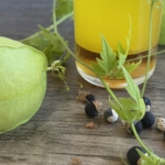 2 farbige Lotion in einerm Glas, Samen und Ballonfrüchte im Vordergrung